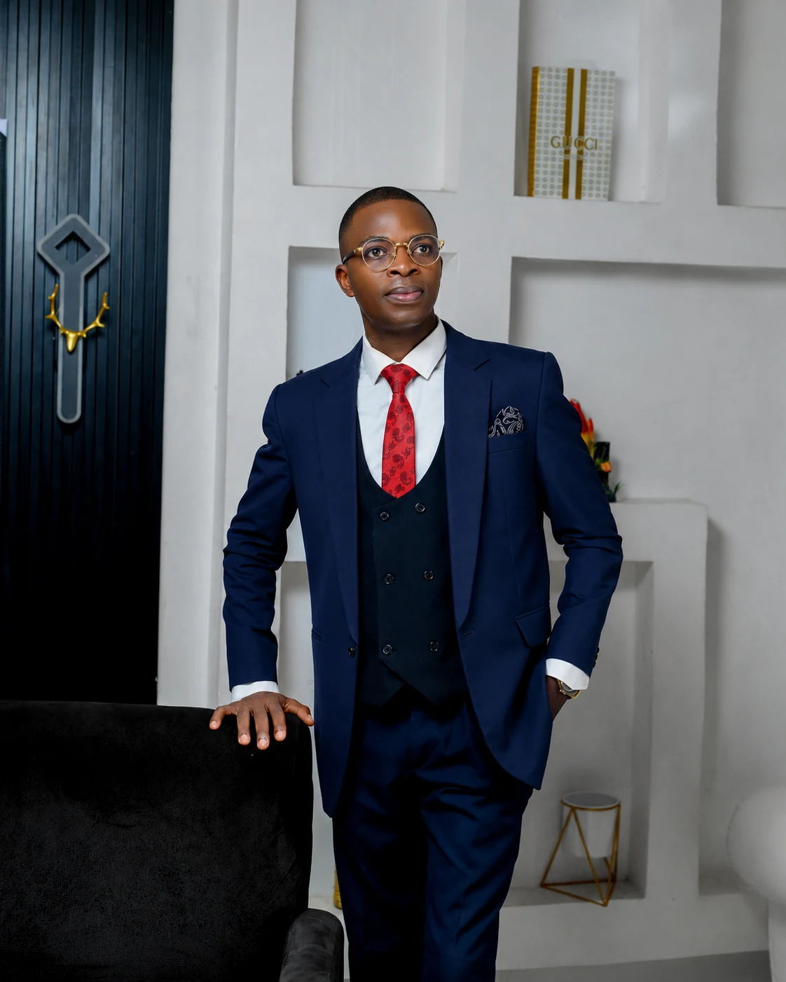 Pastor Folorunso Alesinloye standing in navy suit and red tie, looking upward